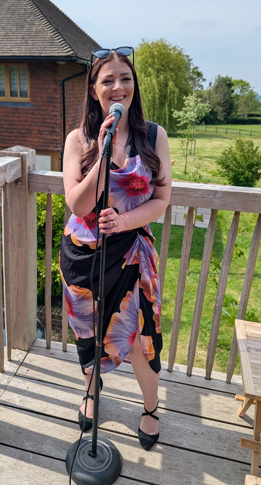 Hayley singing into a microphone outdoors on a sunny deck